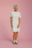 Woman wearing a striped dress against a pink background