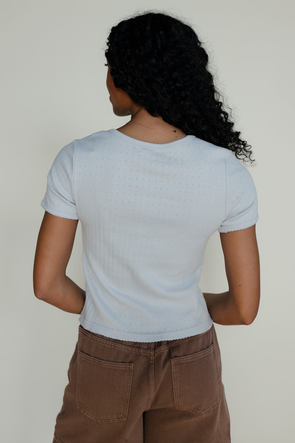 Woman wearing a light blue blouse and brown shorts