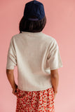 Woman wearing a sweater and skirt against a pink background