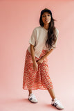 Women wearing a tan sweater and red print skirt