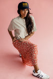 Women wearing a cherry print skirt and trucker hat