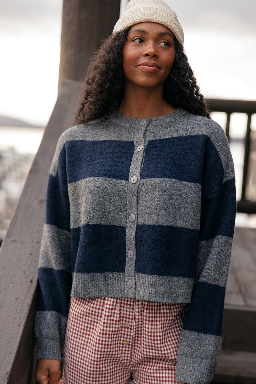 Woman wearing a blue and gray striped sweater with plaid pants, standing outdoors.