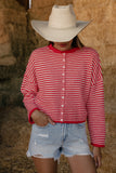 Person wearing a red and white striped shirt, denim shorts, and a cowboy hat in front of hay bales.