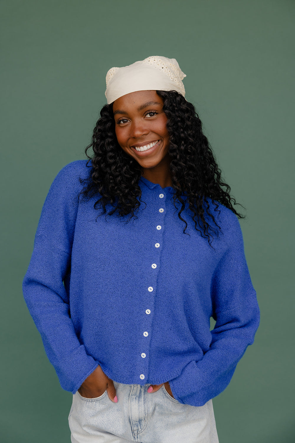 Person wearing a blue cardigan with a plain background