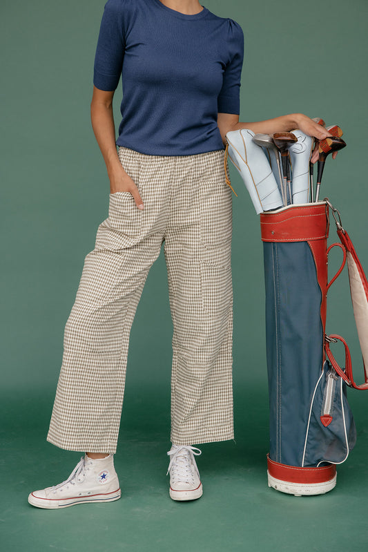 Person holding a golf bag with clubs against a green background
