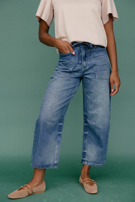 Person wearing blue jeans and a beige top on a green background