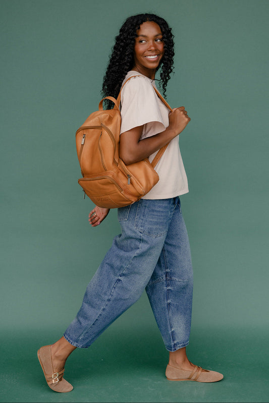 Woman with a brown backpack against a green background