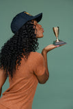 Woman holding a small trophy against a green background