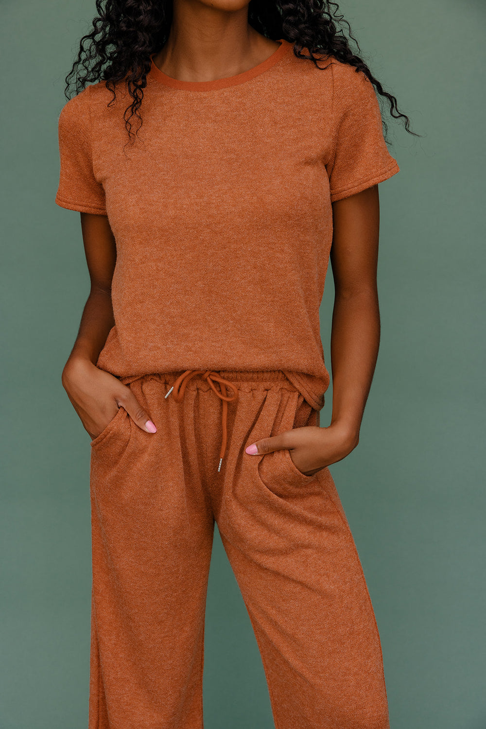 Person wearing a brown outfit against a green background