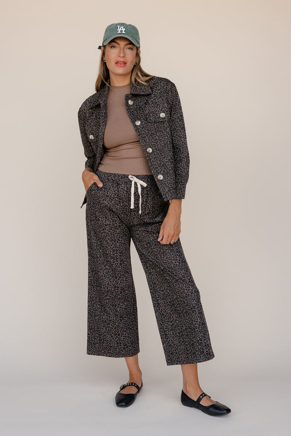 Woman wearing a patterned outfit with a cap on a plain background