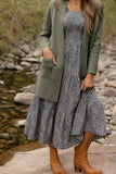 Woman wearing a floral dress with a green cardigan and brown boots by a stream.