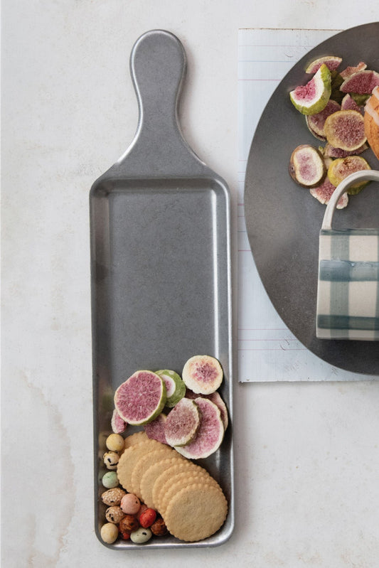 Metal tray with cookies, figs, and a mug on a light surface