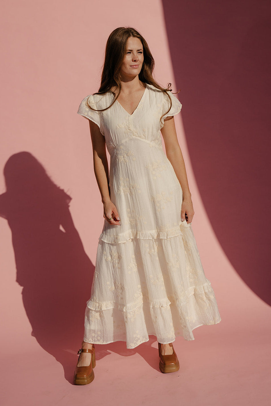 Woman wearing a white dress against a pink background