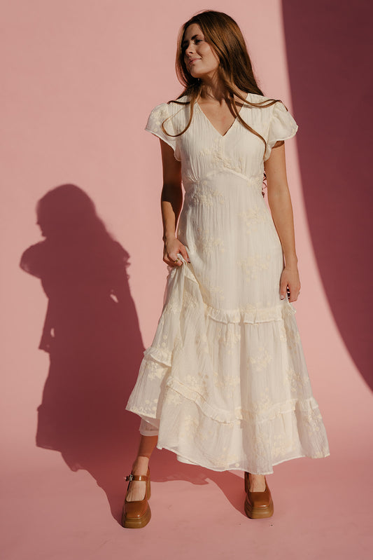 Woman wearing a white dress against a pink background