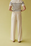 Person wearing a striped shirt and beige pants on a yellow background