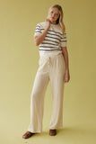 Woman wearing a striped shirt and beige pants against a yellow background