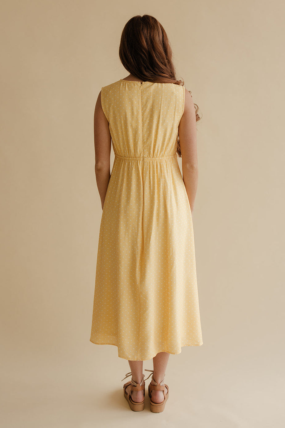 Woman wearing a yellow dress against a beige background