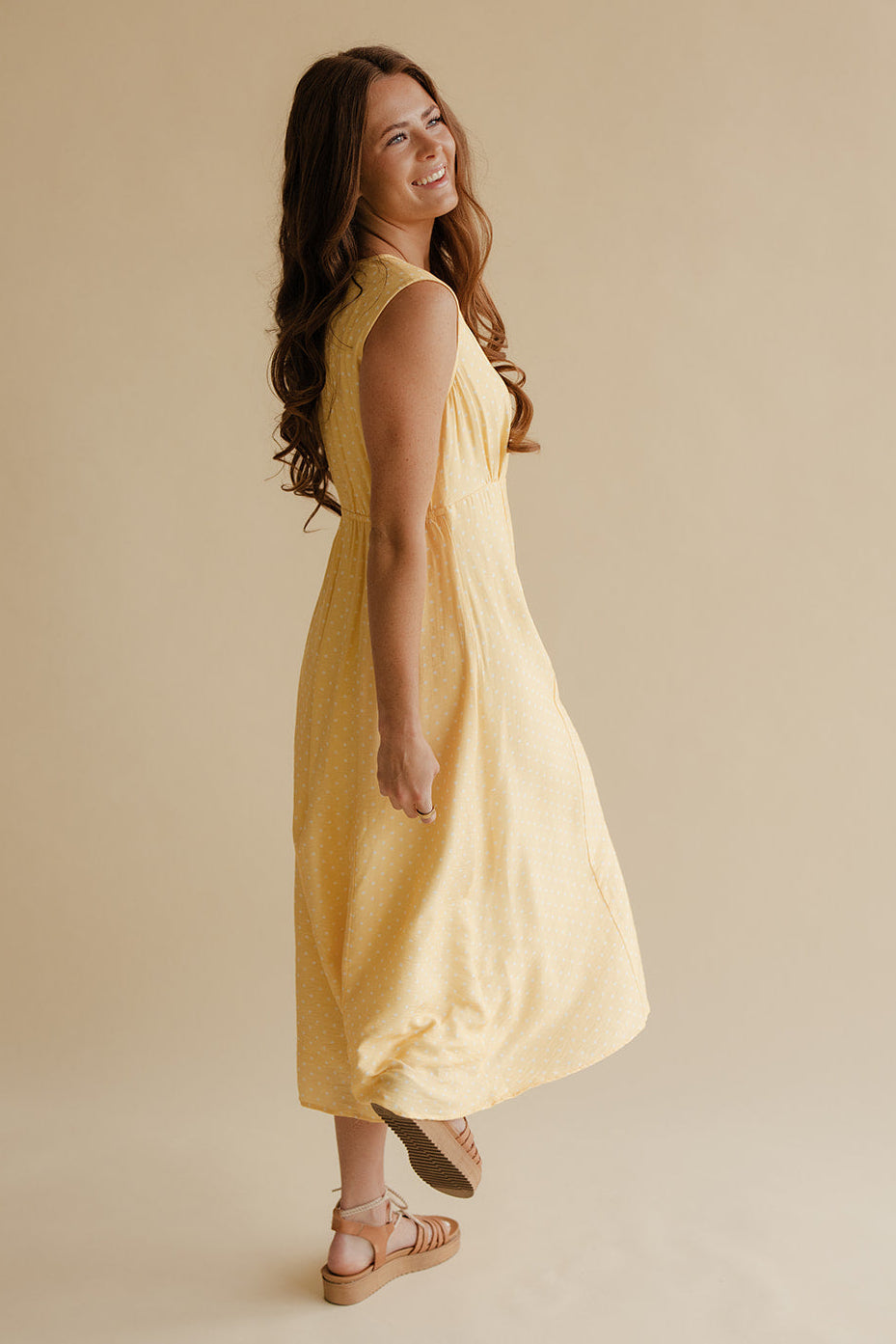 Woman wearing a yellow dress against a beige background