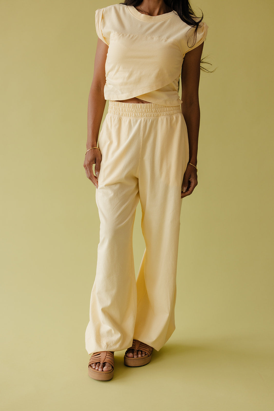 Person wearing a light yellow top and pants on a solid background