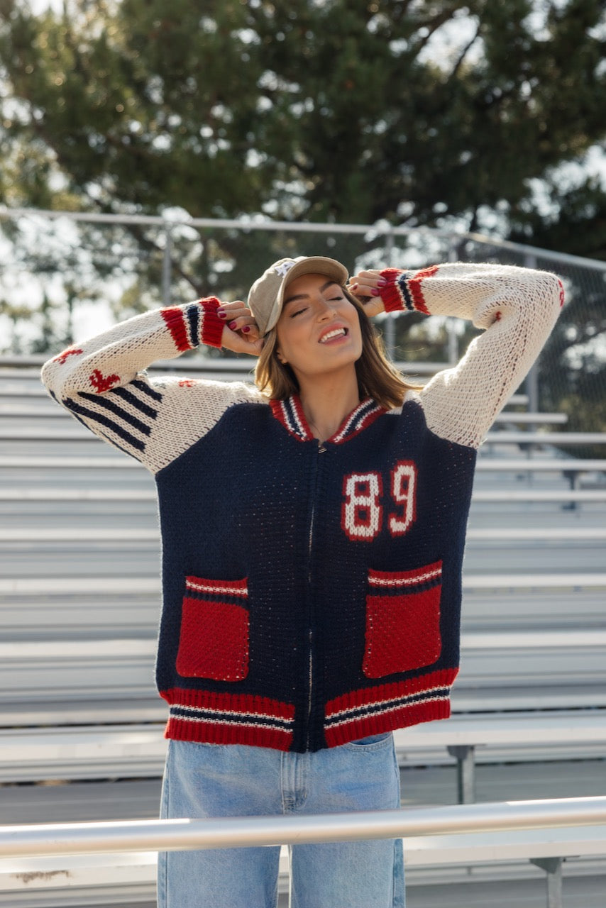 a woman in a sweater with her hands behind her head