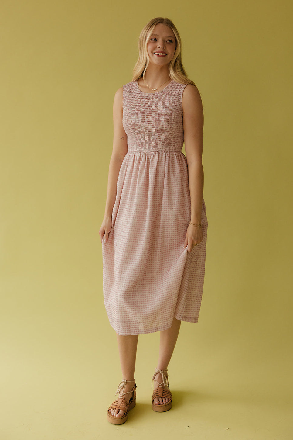 Woman wearing a pink checkered dress against a yellow background
