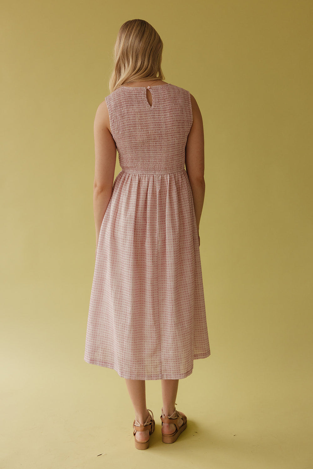 Woman wearing a gingham dress against a green background