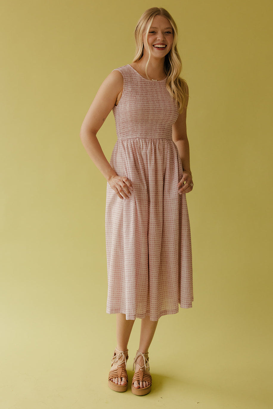 Woman wearing a pink checkered dress against a yellow background