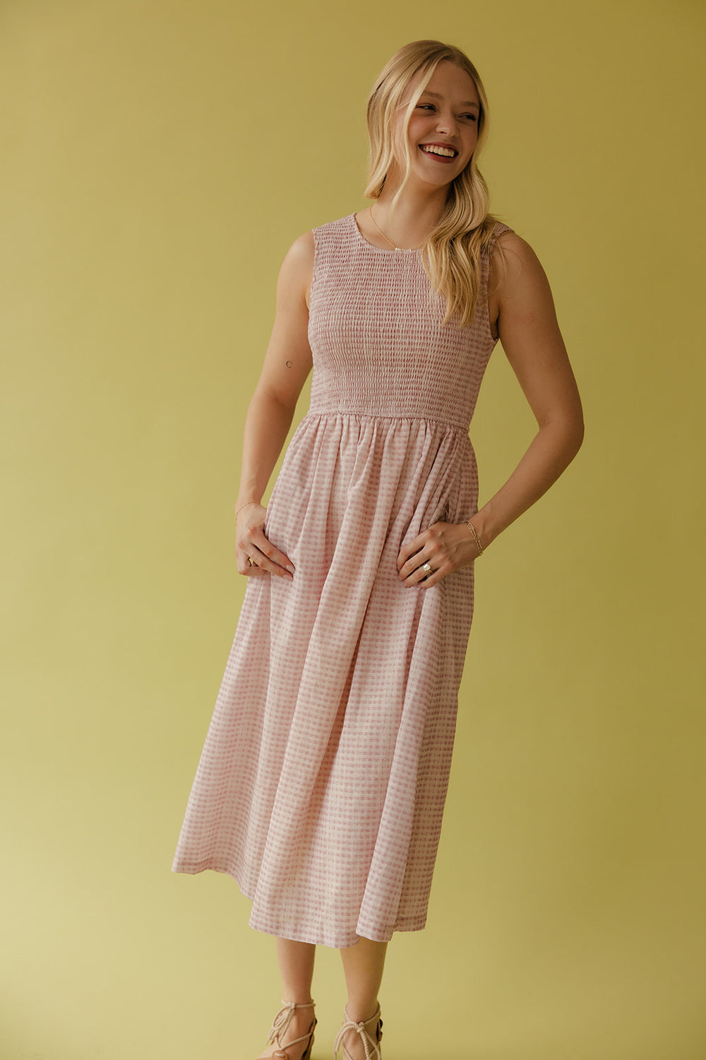 Woman wearing a pink checkered dress against a yellow background
