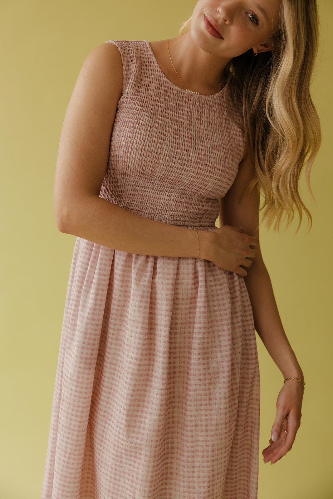 Woman wearing a pink checkered dress against a yellow background