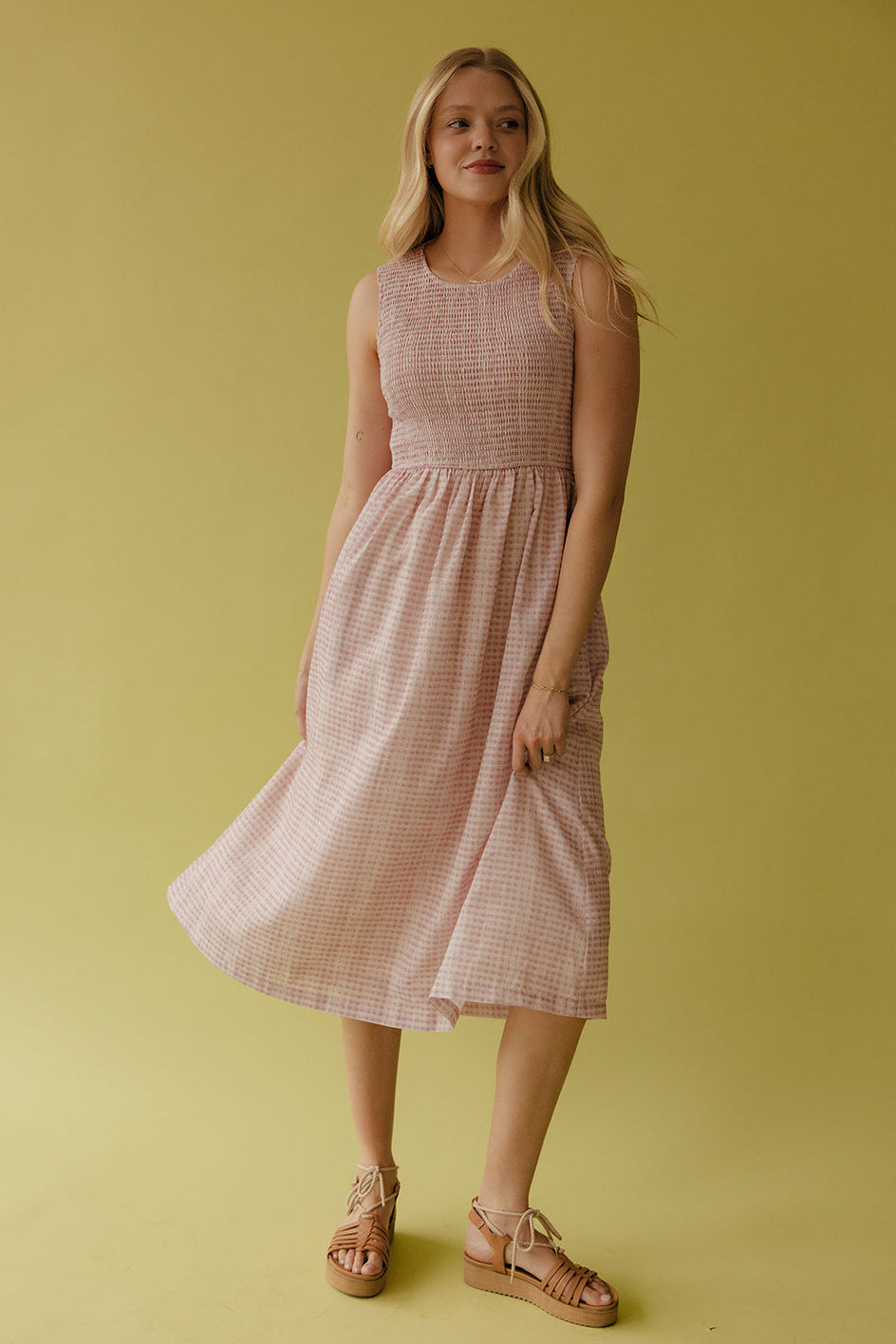 Woman wearing a pink checkered dress against a yellow background