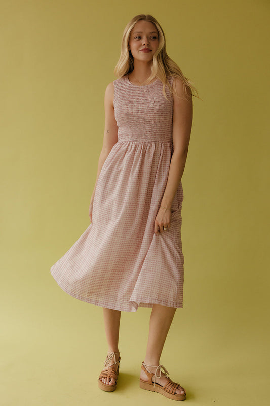 Woman wearing a pink checkered dress against a yellow background