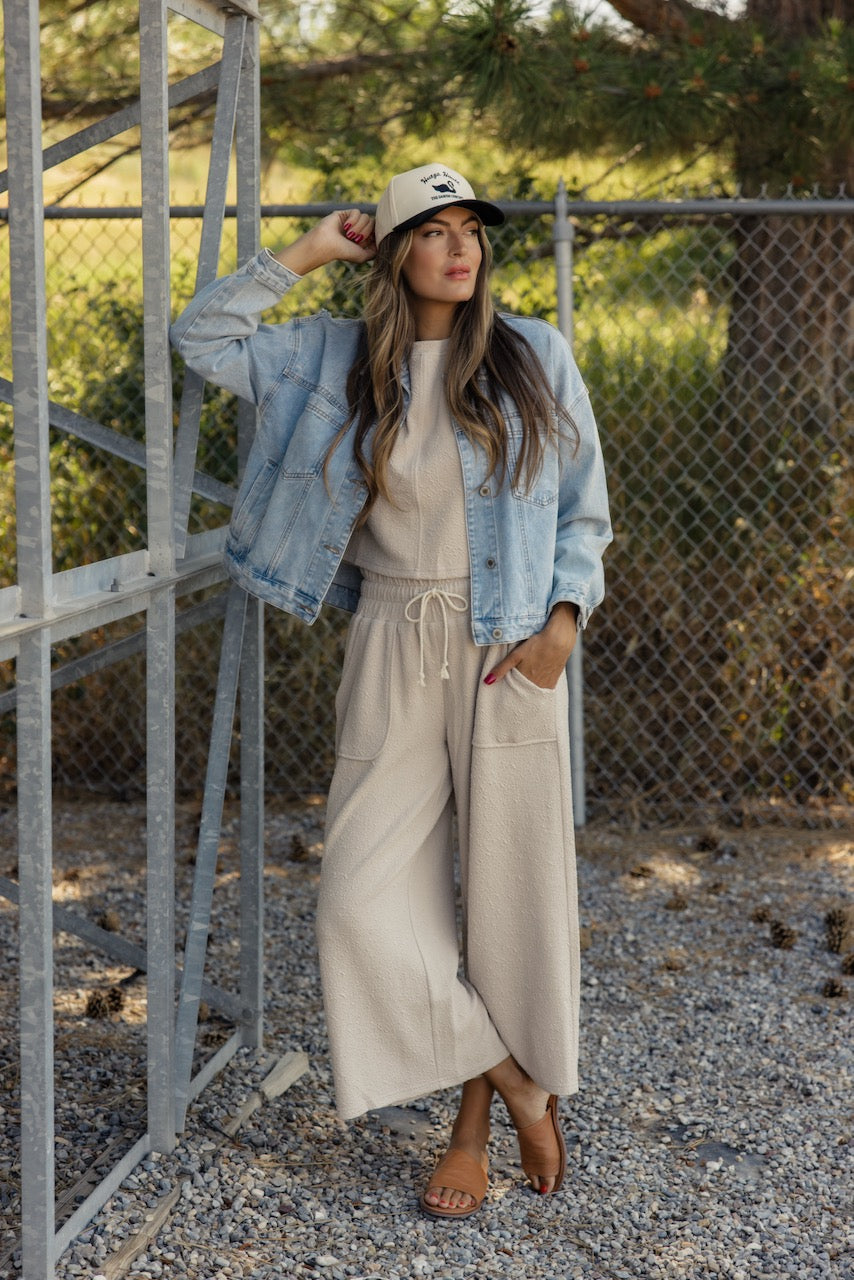 a woman wearing a hat and standing in front of a fence