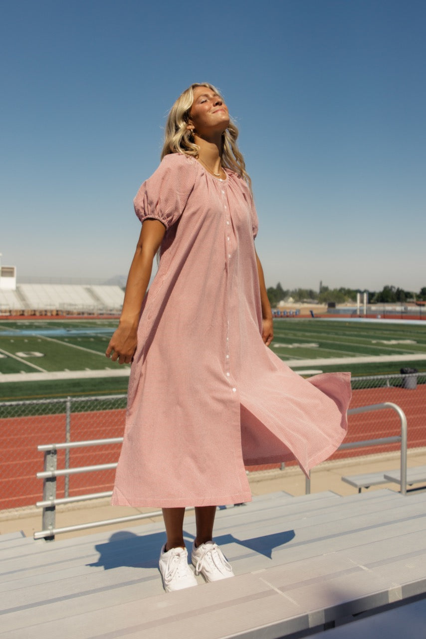 a woman in a pink dress standing on bleachers