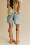 Person wearing denim shorts and tan boots on a beige background