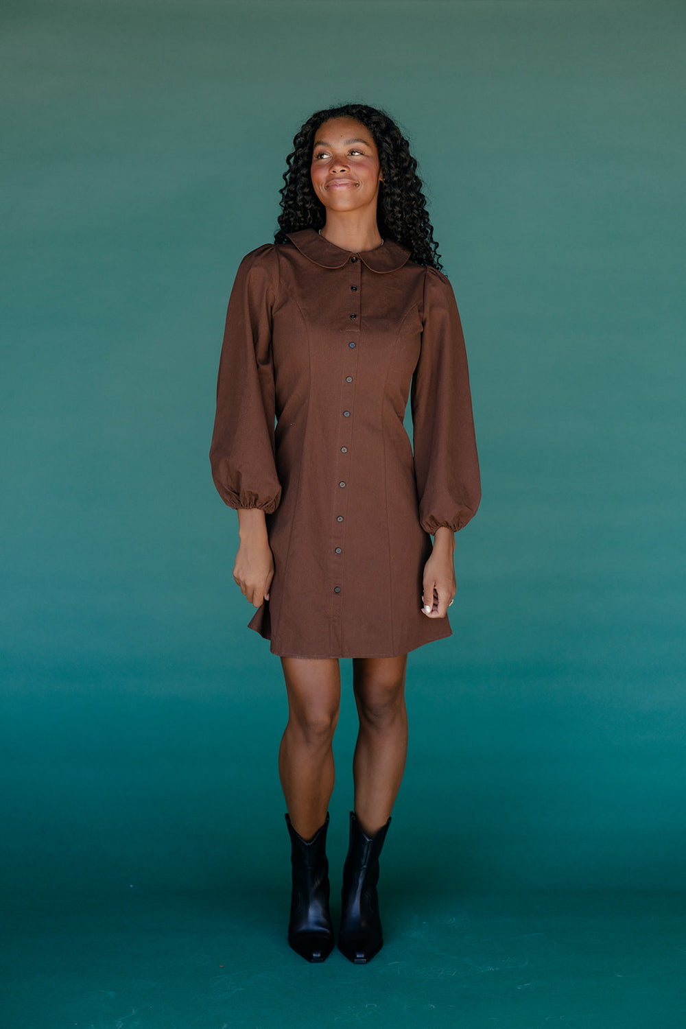 Woman wearing a brown dress against a teal background