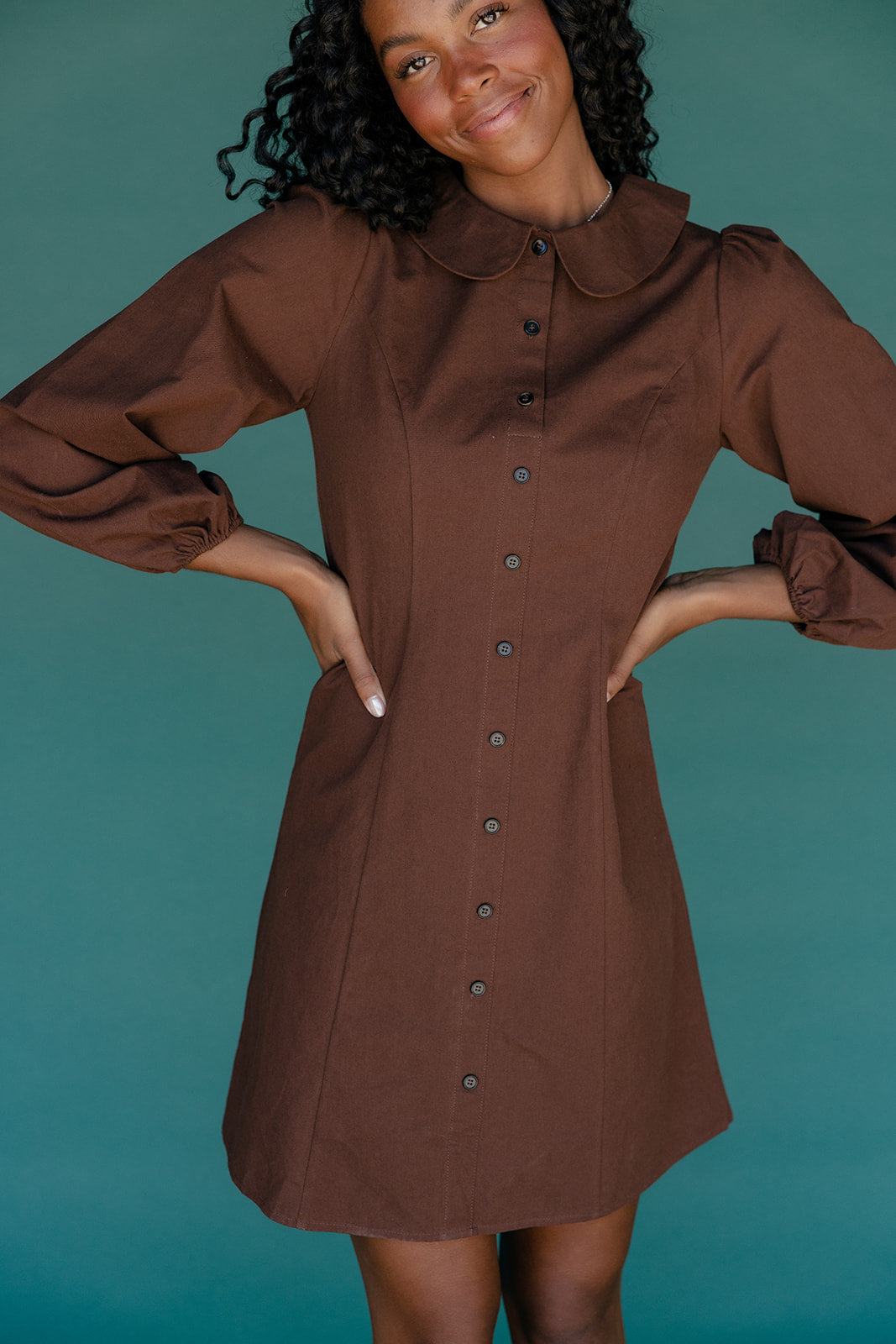 Woman wearing a brown dress against a teal background