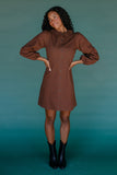 Woman wearing a brown dress against a teal background