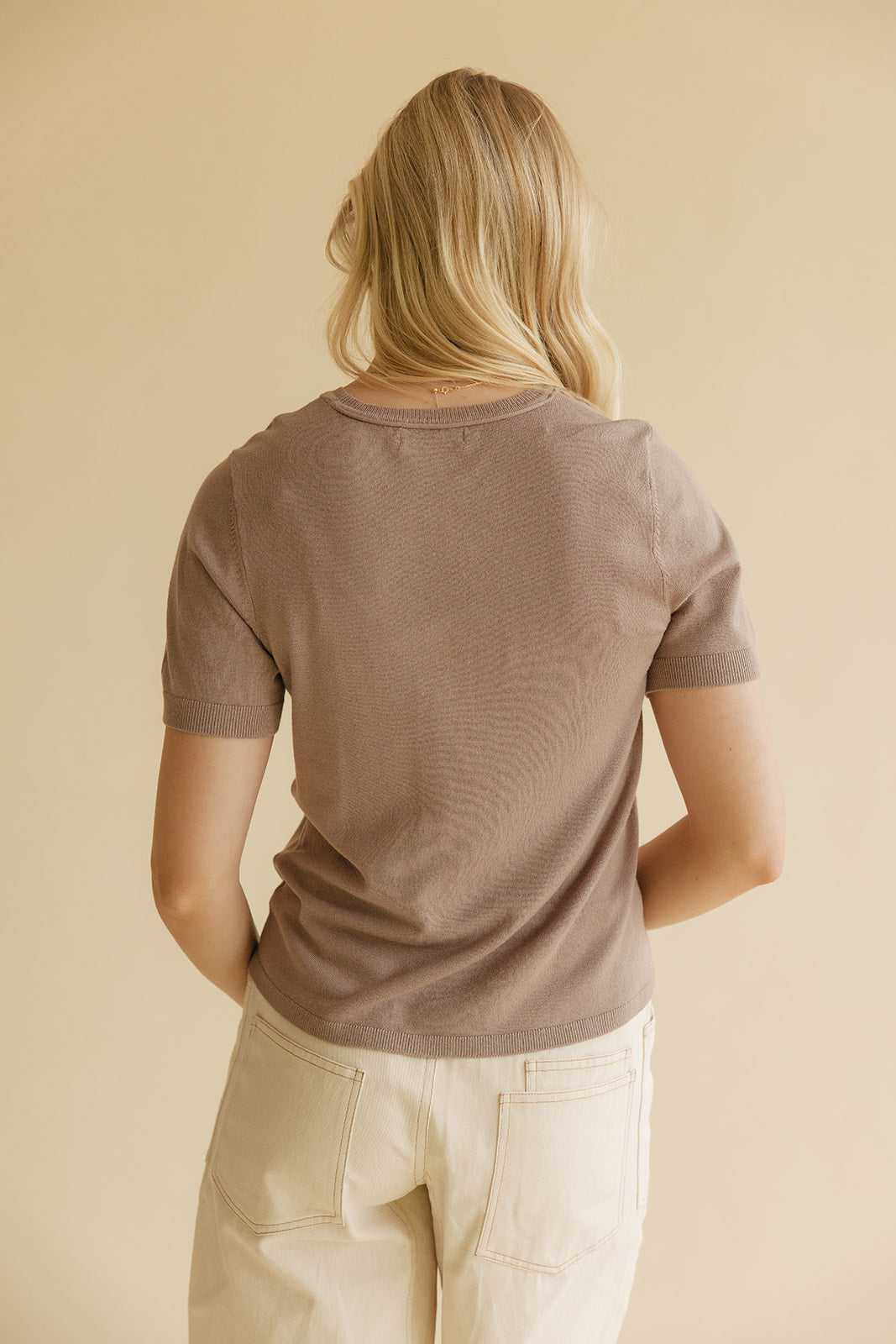 Blonde woman wearing ivory shorts with a brown tee