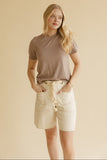 Woman wearing a brown shirt and ivory shorts