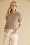 Woman wearing a brown tee and ivory shorts on a yellow background