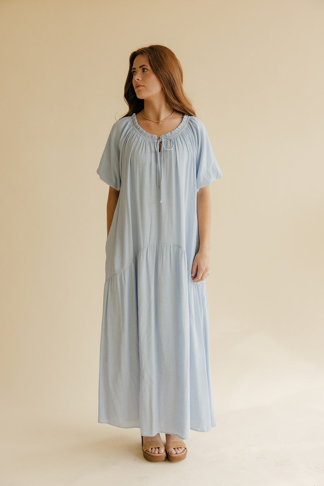 Woman wearing a light blue dress against a beige background