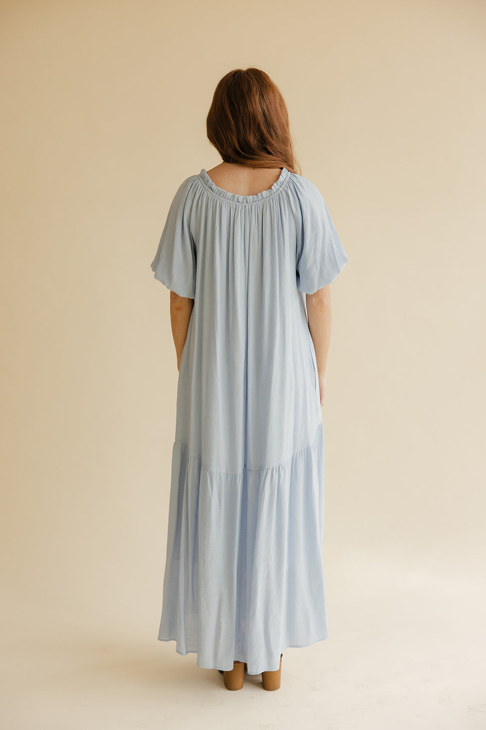 Woman wearing a light blue dress against a beige background