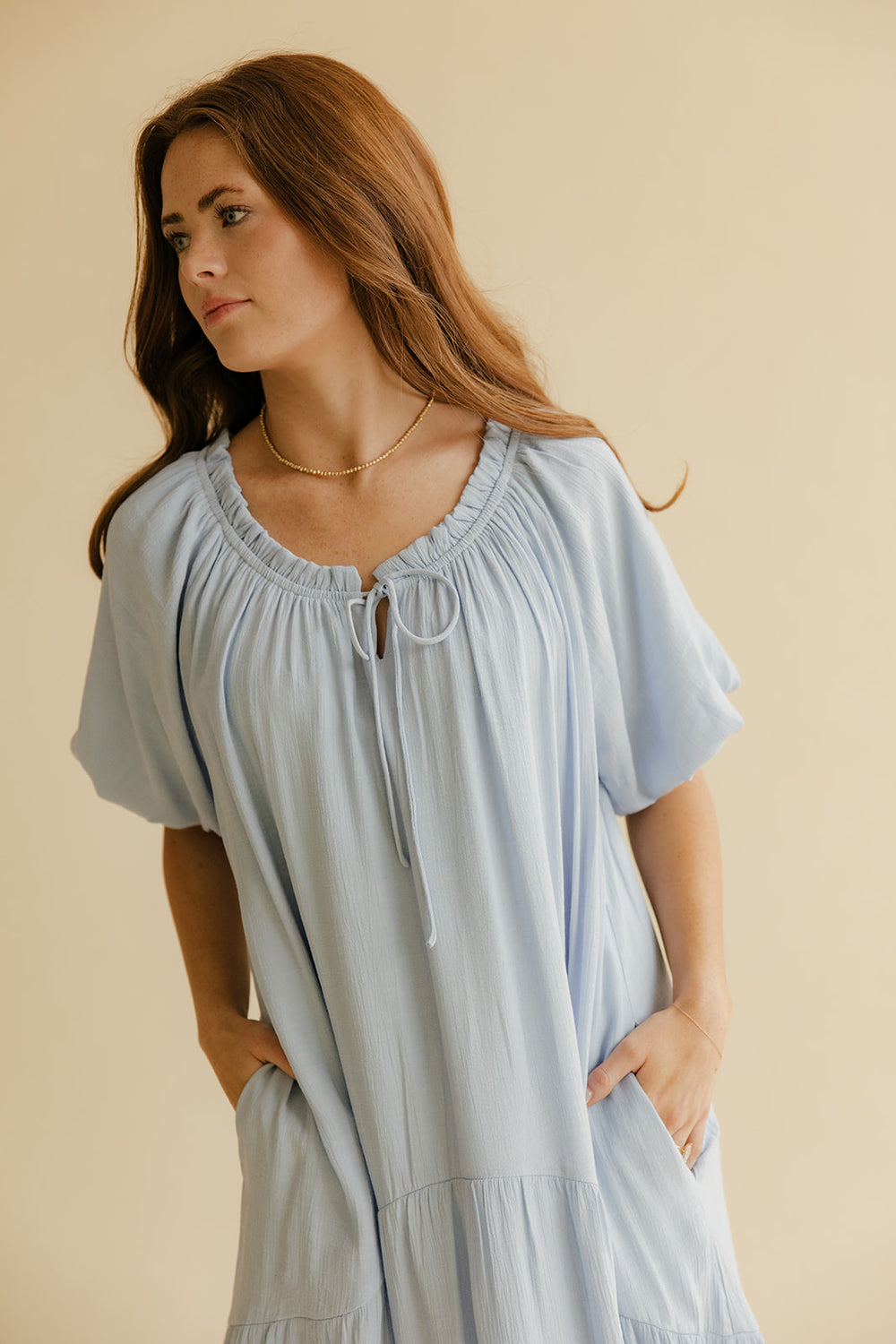 Woman wearing a light blue dress against a beige background