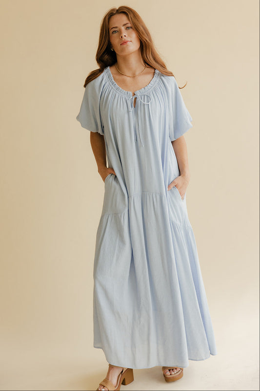 Woman wearing a light blue dress against a beige background