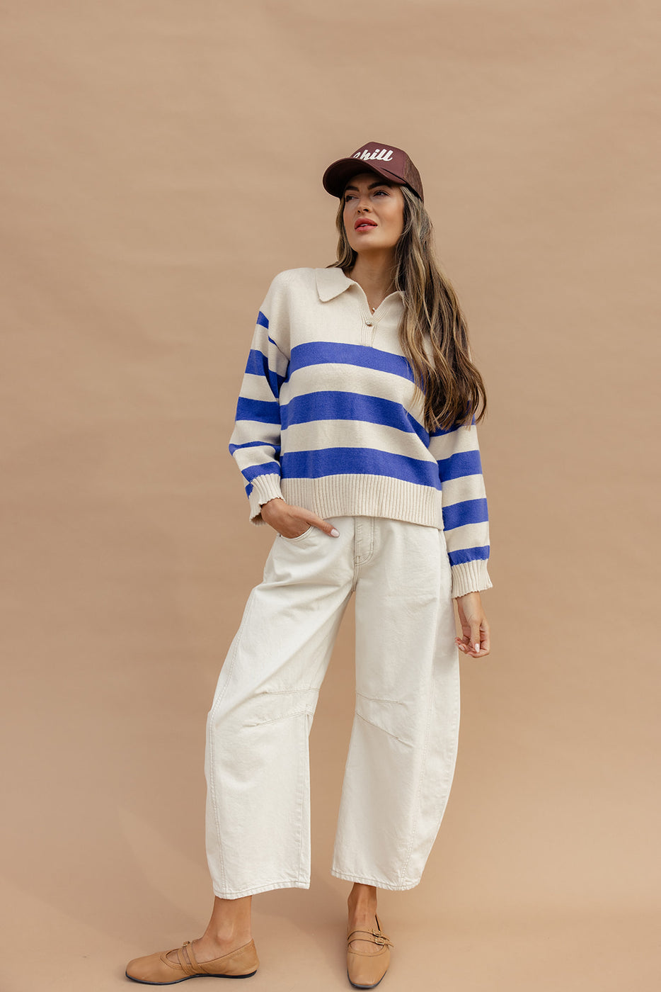 a woman in a blue and white striped sweater and white pants