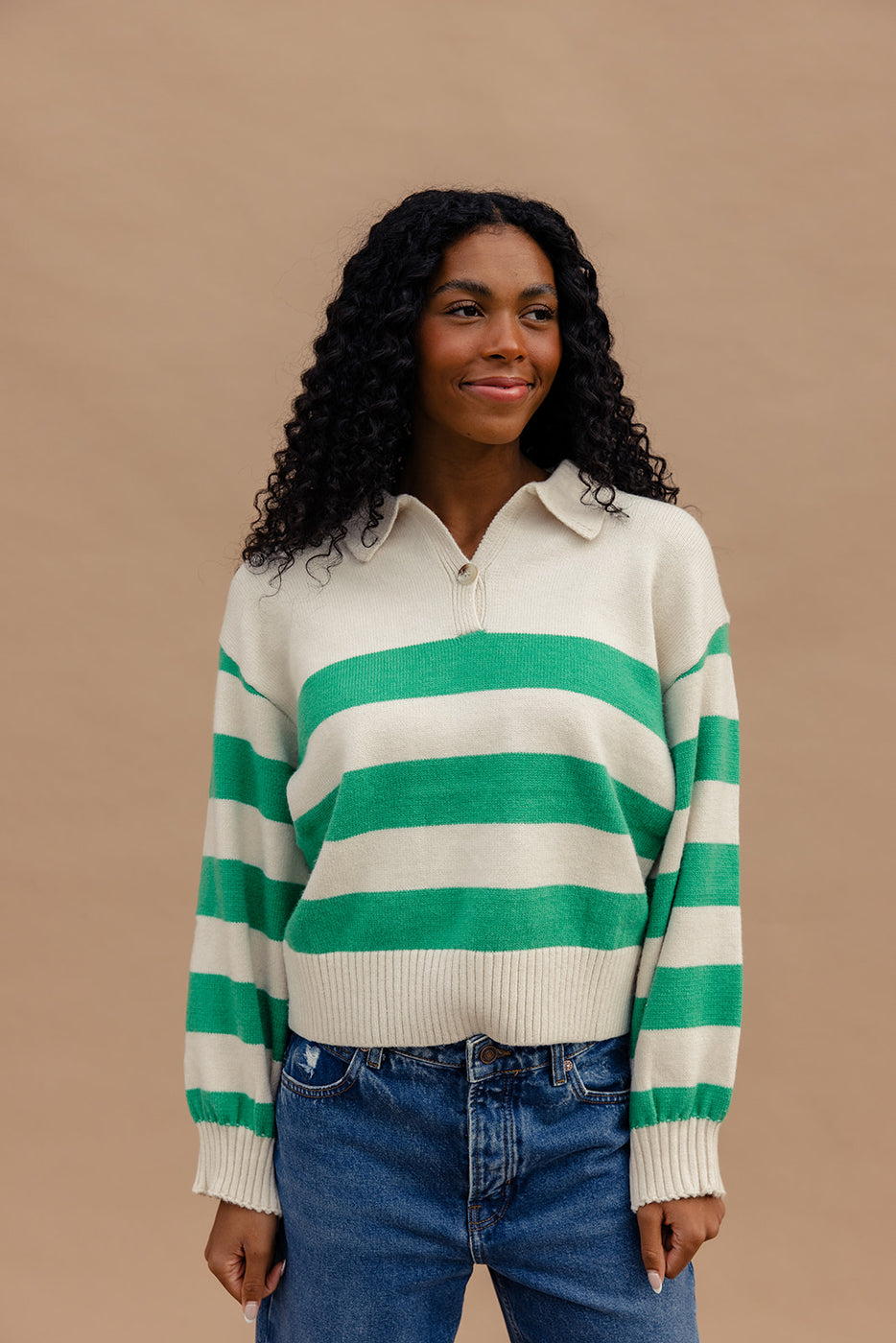 a woman with long curly hair wearing a green and white striped sweater