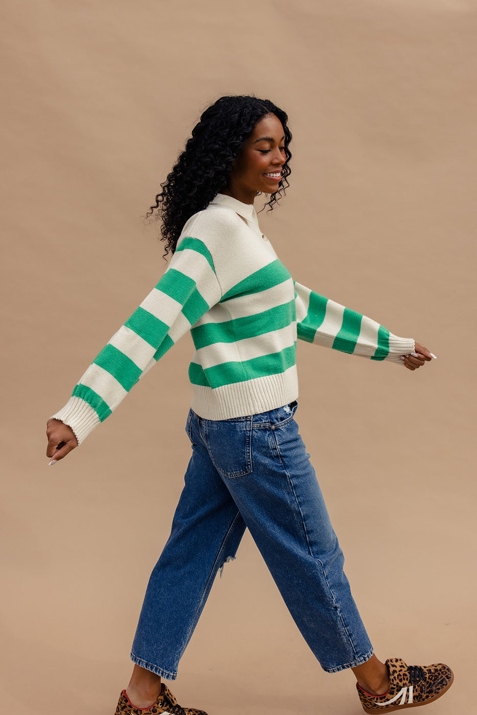 a woman wearing a green and white striped sweater and blue jeans