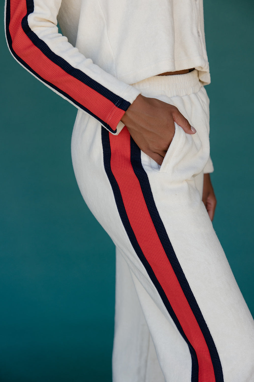 White pants with red and navy stripes on a teal background