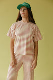 Person wearing a striped shirt and pants with a green cap against a yellow background