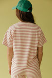 Person wearing a green cap and pink striped shirt and pants on a yellow background